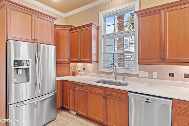 kitchen with light countertops, a sink, appliances with stainless steel finishes, and crown molding