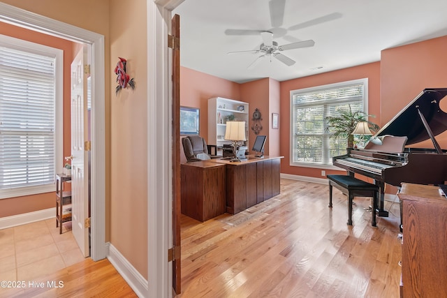 office area with light wood-type flooring, a ceiling fan, and baseboards