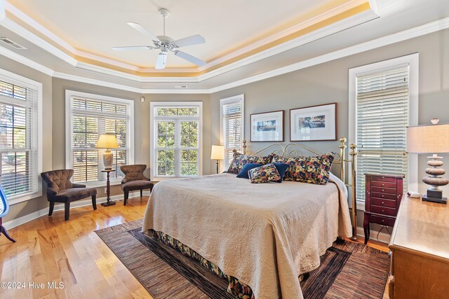 bedroom with crown molding, a raised ceiling, ceiling fan, and hardwood / wood-style flooring