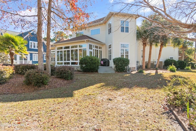 back of house featuring a sunroom and a lawn