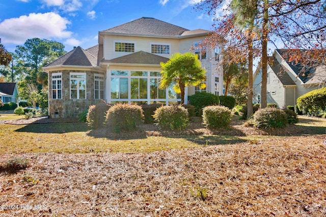 back of house featuring a sunroom and a lawn