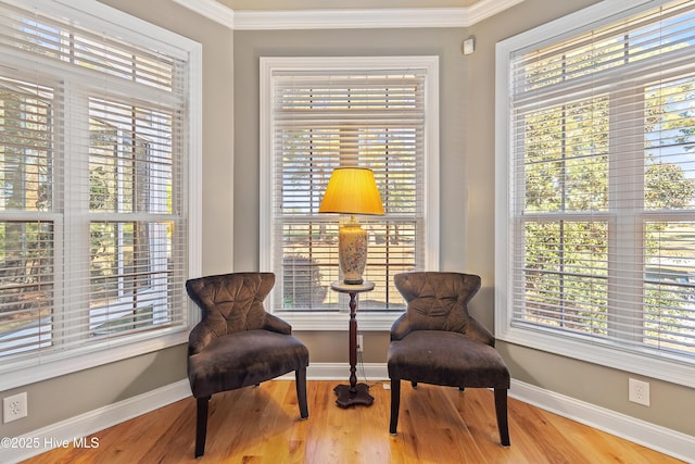 living area with ornamental molding, baseboards, a healthy amount of sunlight, and wood finished floors