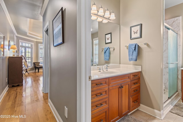 bathroom featuring baseboards, wood finished floors, vanity, and a stall shower