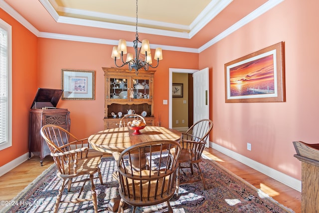 dining area featuring a tray ceiling, light wood-style floors, and crown molding