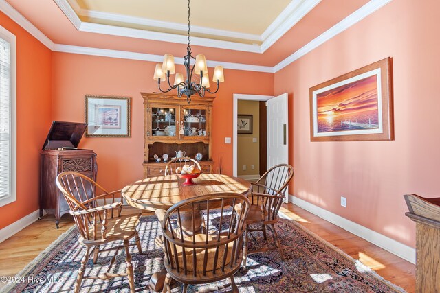 dining area with a chandelier, ornamental molding, and a raised ceiling