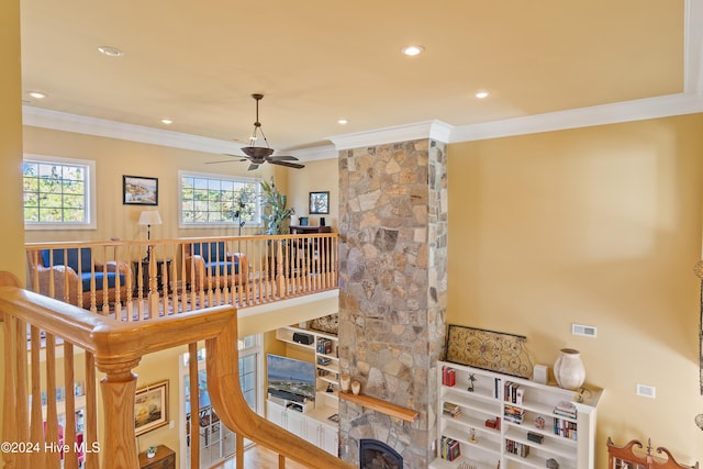 staircase with crown molding, a stone fireplace, recessed lighting, and a healthy amount of sunlight