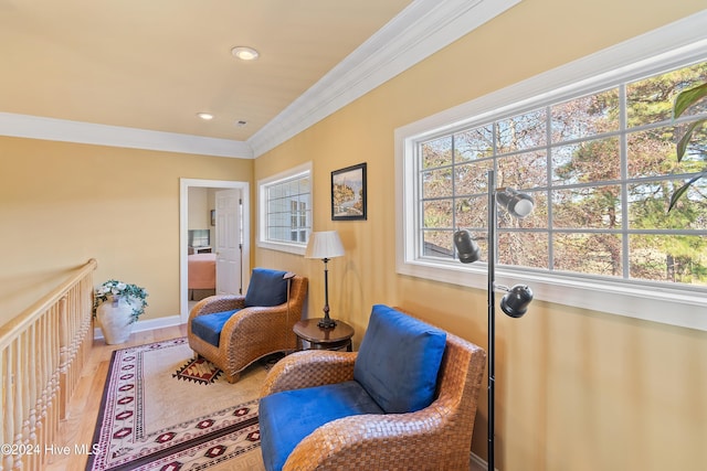 sitting room featuring baseboards, wood finished floors, a wealth of natural light, and crown molding