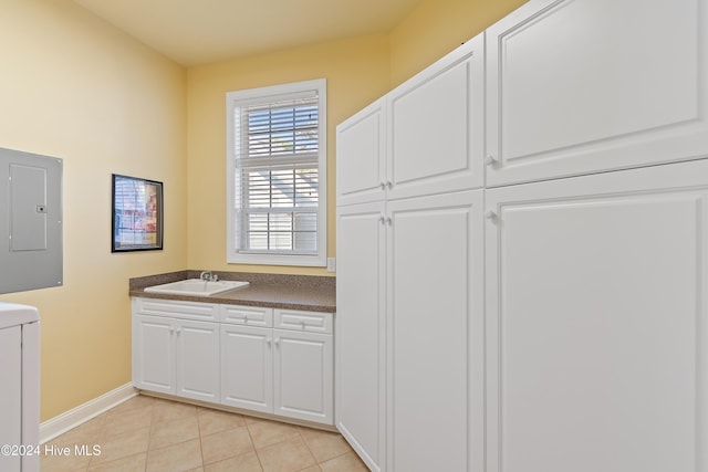 interior space with washer / clothes dryer, light tile patterned flooring, a sink, electric panel, and baseboards