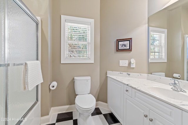 bathroom featuring tile patterned floors, a shower with door, toilet, vanity, and baseboards