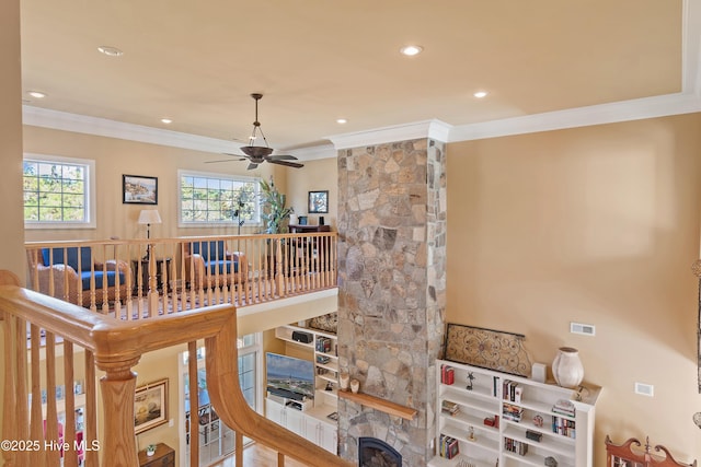room details featuring a ceiling fan, a stone fireplace, recessed lighting, and ornamental molding