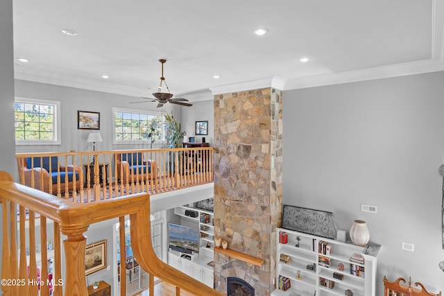 stairs with a stone fireplace, ornamental molding, a ceiling fan, and recessed lighting