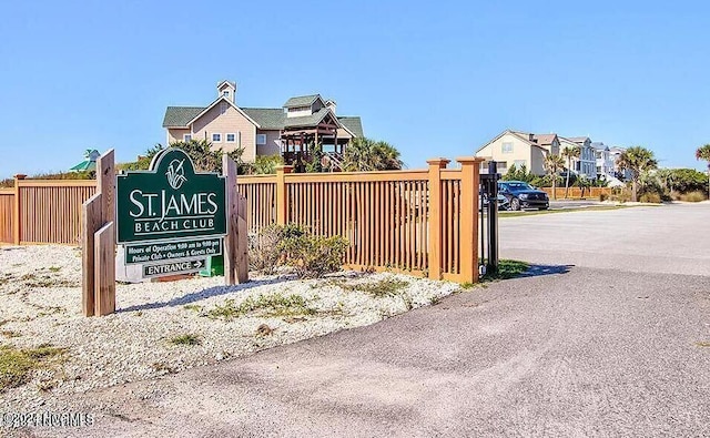 community / neighborhood sign featuring a residential view and fence