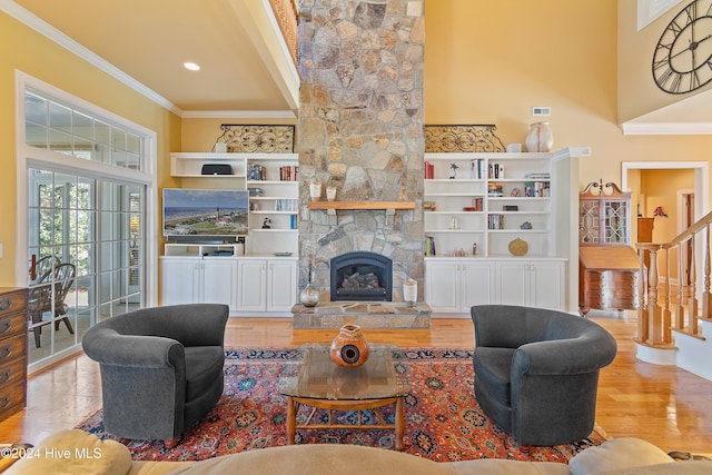 living room with a stone fireplace, stairway, wood finished floors, and crown molding