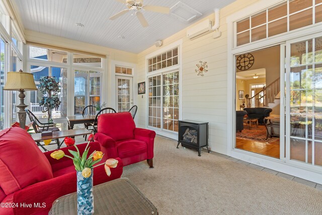 sunroom with a wood stove, tile patterned floors, a wall mounted AC, and carpet