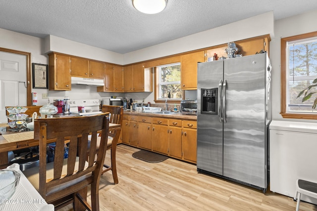 kitchen featuring sink, stainless steel refrigerator with ice dispenser, white range with electric cooktop, a textured ceiling, and light wood-type flooring