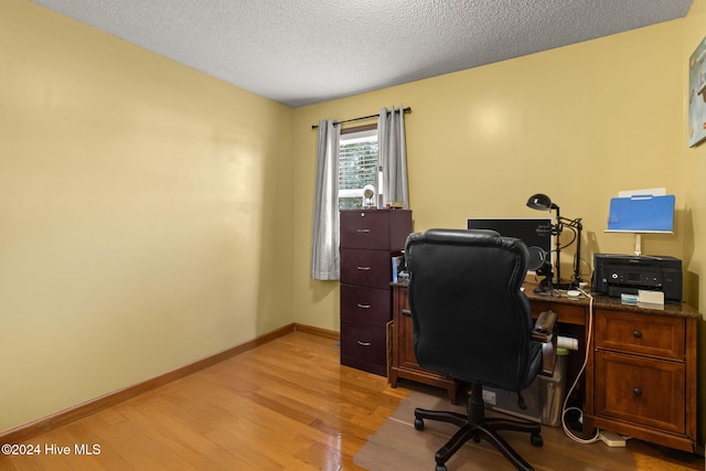 home office with light wood-type flooring and a textured ceiling