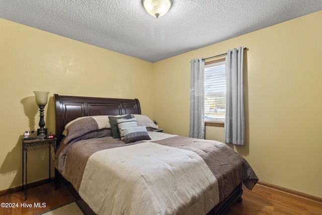 bedroom with dark hardwood / wood-style flooring and a textured ceiling