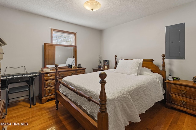 bedroom featuring dark hardwood / wood-style flooring, a textured ceiling, and electric panel