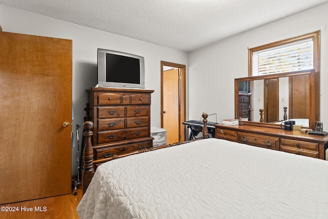 bedroom with a textured ceiling and light hardwood / wood-style floors