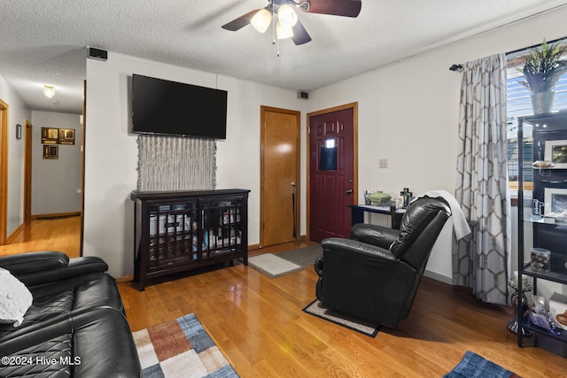 living room with a textured ceiling, light hardwood / wood-style floors, and ceiling fan