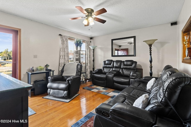 living room featuring ceiling fan, wood-type flooring, and a textured ceiling