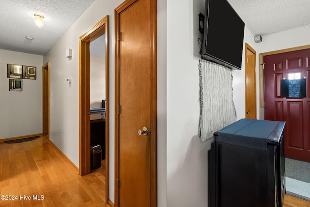 corridor with light hardwood / wood-style floors and a textured ceiling