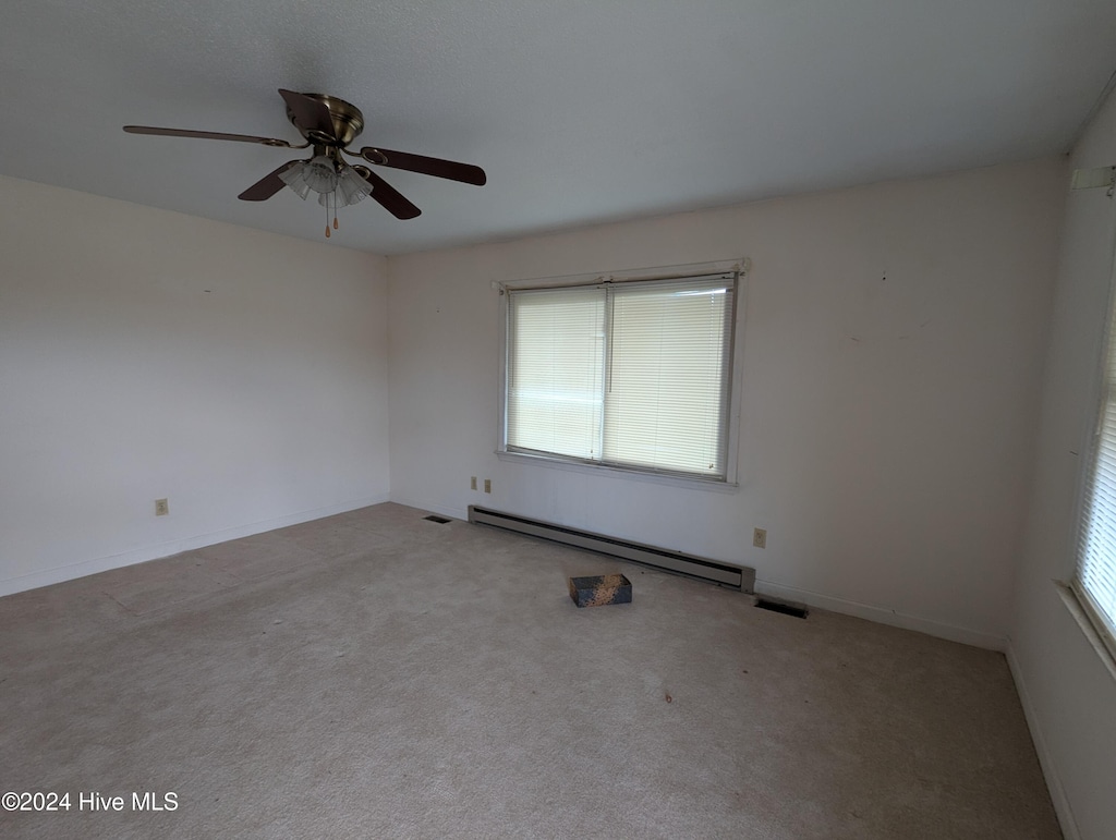 carpeted spare room with ceiling fan and a baseboard radiator