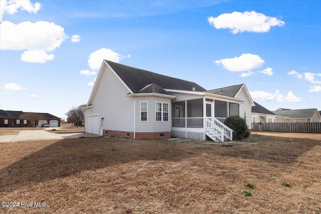 back of house with a sunroom, a garage, and a yard