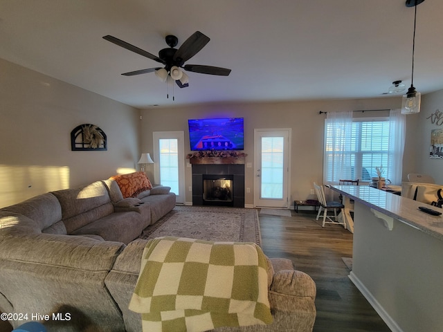 living room with ceiling fan, dark wood-type flooring, and a tiled fireplace