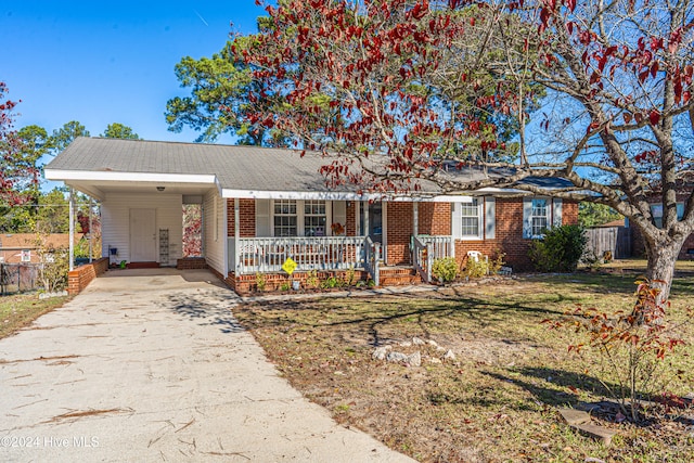 ranch-style house featuring a carport, a porch, and a front lawn