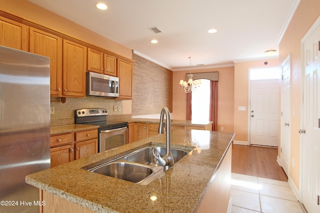 kitchen featuring sink, a chandelier, decorative light fixtures, appliances with stainless steel finishes, and ornamental molding