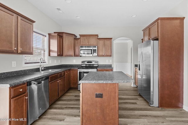 kitchen with a kitchen island, sink, dark wood-type flooring, and appliances with stainless steel finishes