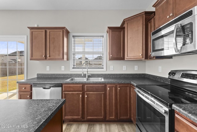 kitchen featuring appliances with stainless steel finishes, light hardwood / wood-style flooring, a healthy amount of sunlight, and sink