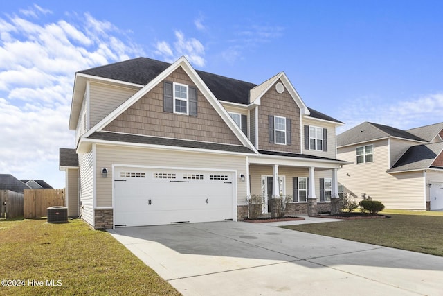 craftsman-style home with cooling unit, a front yard, and a garage