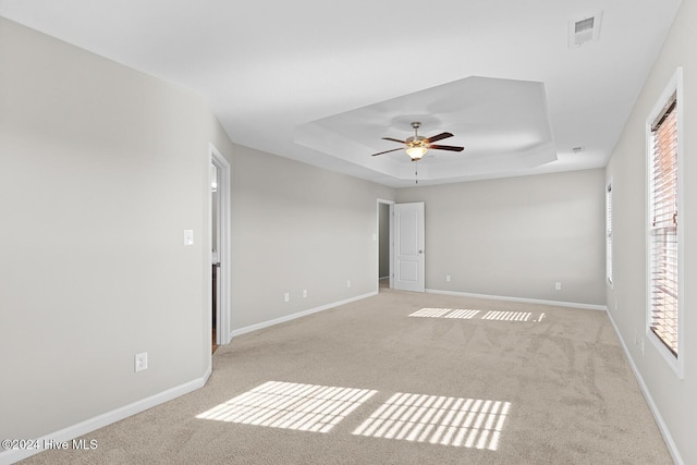 carpeted empty room featuring a raised ceiling and ceiling fan