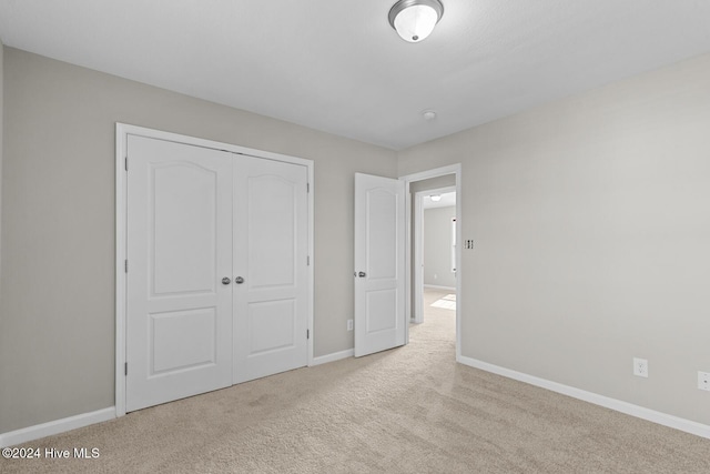 unfurnished bedroom featuring light carpet and a closet