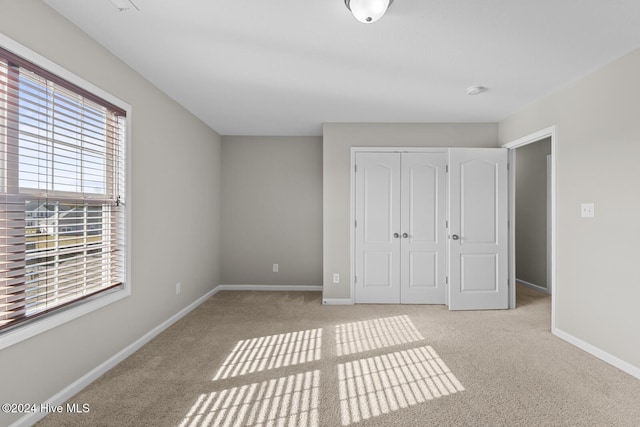 unfurnished bedroom with multiple windows, a closet, and light colored carpet