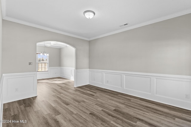 spare room featuring dark hardwood / wood-style flooring, ornamental molding, and an inviting chandelier