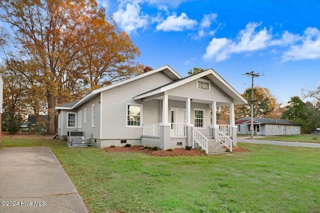 view of front of house featuring central AC, a front lawn, and covered porch