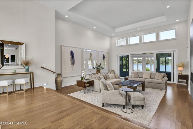 living room with a water view, french doors, a high ceiling, and hardwood / wood-style floors