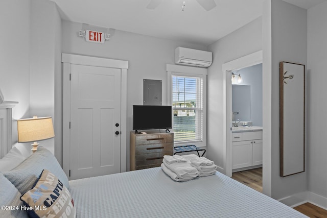 bedroom featuring light wood-type flooring, ensuite bathroom, ceiling fan, sink, and an AC wall unit