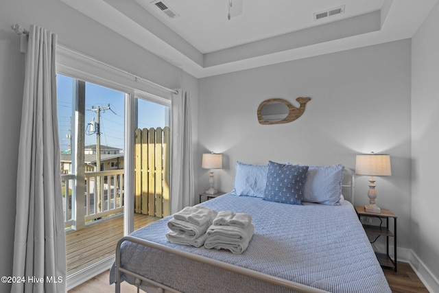 bedroom with a tray ceiling and wood-type flooring