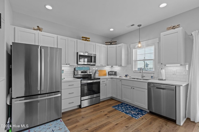 kitchen with sink, hanging light fixtures, dark wood-type flooring, stainless steel appliances, and white cabinets