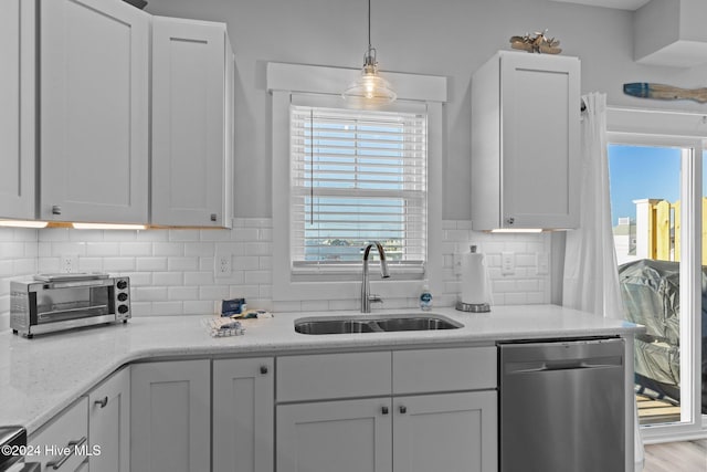 kitchen with decorative light fixtures, white cabinetry, stainless steel dishwasher, and sink