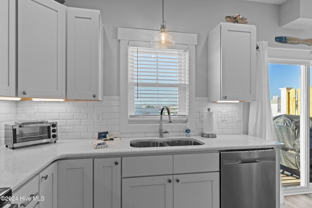 kitchen with stainless steel dishwasher, tasteful backsplash, white cabinetry, and a sink