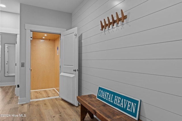 corridor with wooden walls and light hardwood / wood-style floors