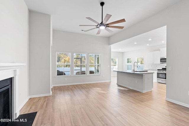 unfurnished living room with ceiling fan, light wood-type flooring, and sink