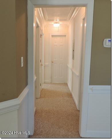 hallway with ornamental molding and light carpet