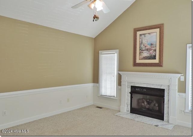 unfurnished living room with light colored carpet, vaulted ceiling, ceiling fan, and a premium fireplace