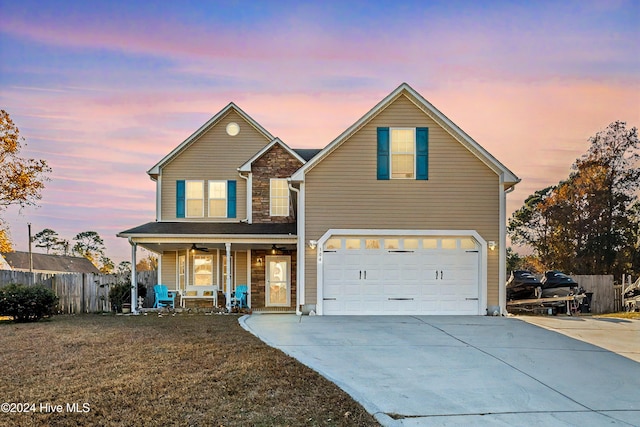 front of property with covered porch, a garage, and a yard